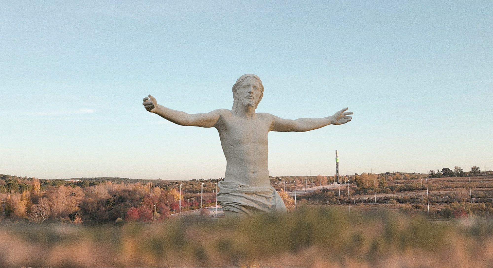 La escultura monumental del Corazón de Jesús con los brazos abiertos, al atardecer sobre el paisaje.