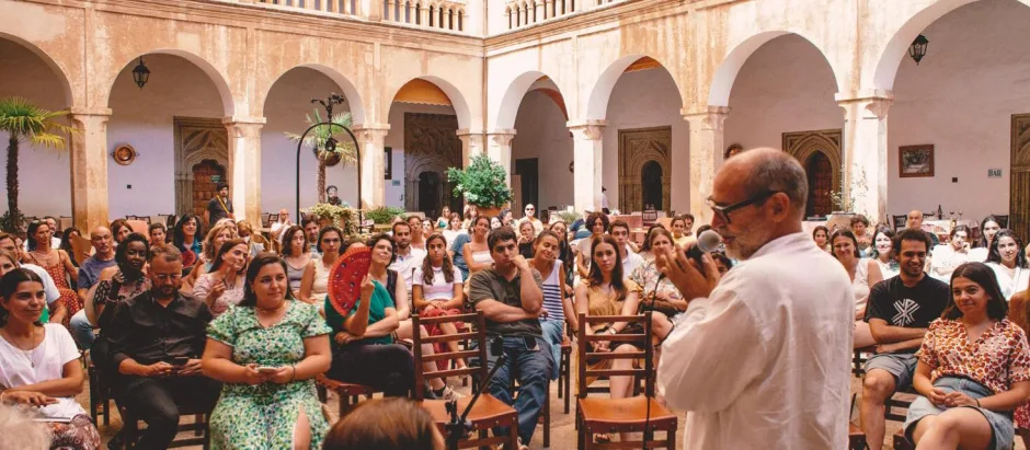 Javier Viver, de espaldas y con micrófono, se dirige al centenar de asistentes sentados en el claustro del Monasterio de Guadalupe.