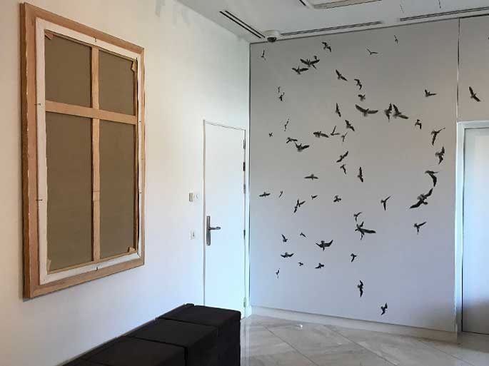 Pared de la capilla con la constelación de aves de David Jiménez y el cuadro en forma de cruz de Mateo Maté.