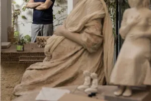 Javier Viver, de brazos cruzados al fondo del taller, junto a una gran talla en barro de la Virgen sentada.