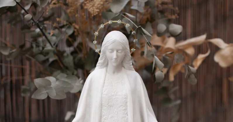 La Virgen con una aureola de estrellas doradas entre ramas de eucalipto.
